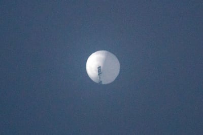 En lite suddig bild på en rund, vit ballong mot mörkblå himmel.
