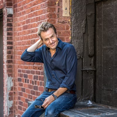 Fredrik Skavlan framför en gammal tegelbyggnad.
