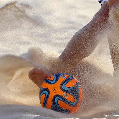 Pelaajat tavoittelevat palloa hiekalla. 
