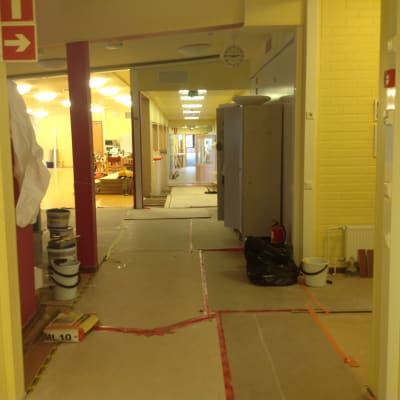 En skola som renoveras. Det är papp på golvet och målarburkar.
