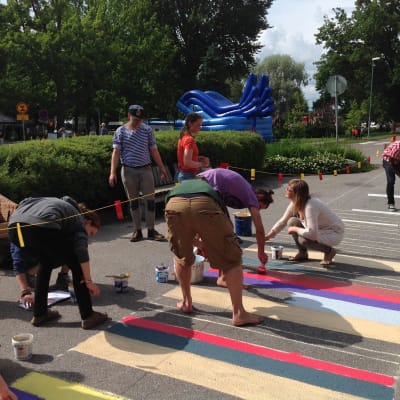 Människor målar en matta på asfalten.