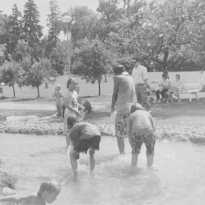Nostalgibild från Äventyrsparken. Bilden är svartvit, flera barn skvätter vatten i bäcken. 
