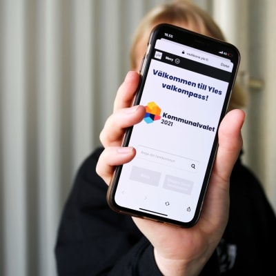 Någon visar valkompassen på mobilen.