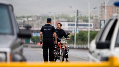 En polis stoppar en man av uiguriskt ursprung i Xinjiang. 