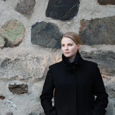 Mia Anderssén-Löf står framför en murad stenvägg. 