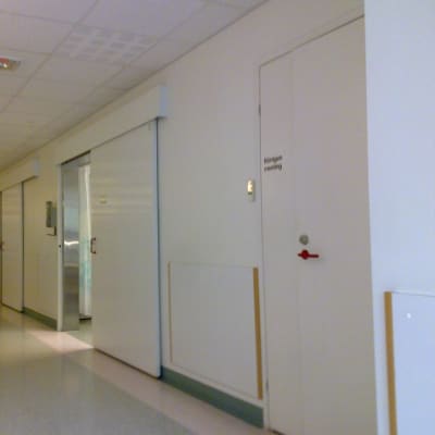 En sjukhuskorridor med dörrar till undersökningsrum.