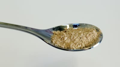 Beigefärgat proteinpulver i en sked.