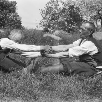 Två män leker leken "vetukapul", som är en slags dragkamp. Bilden är tagen 1929 i Strömfors, Kungsböle.