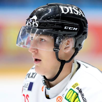 Närbild på ishockeyspelare med svart hjälm och vit speldräkt