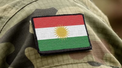 Kurdistans randiga röd-vit-gröna flagga med en gul sol i mitten.