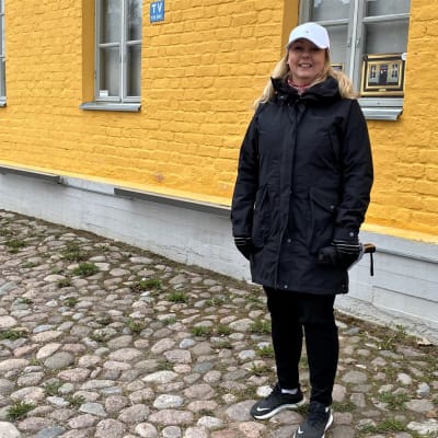 Lappeenrannan kaupngin kaavasuunnittelija Hanna-Maija Marttinen seisoo Lappeenrannan Linnoituksessa. Taustalla keltainen talo.