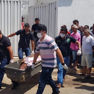 En människogrupp bär ett av dödsoffren i bankrånet i Milagres i Brasilien.