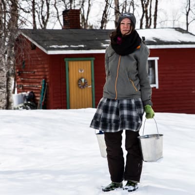 Katja Jomppanen ämpärit kädessä Turvejärven luontaistilan pihassa.