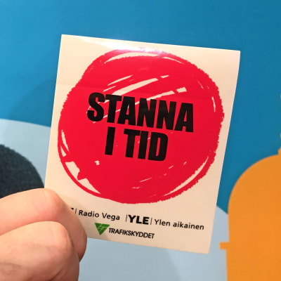 Mikael Kokkola visar upp ett klistermärke från kampanjen Stanna i tid.