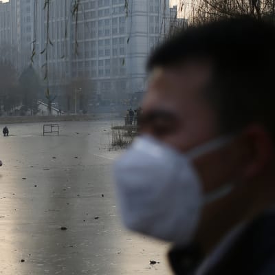 En man iklädd mask vid en frusen flod i Peking 16.12.2016