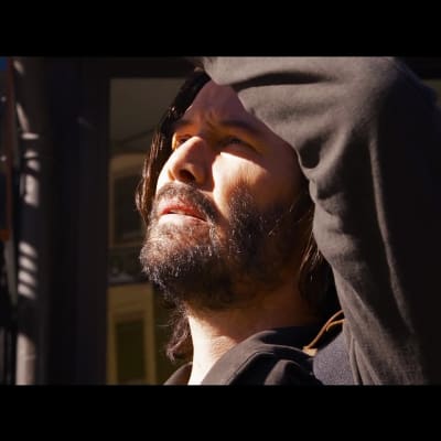 Keanu Reeves som Neo i filmen The Matrix Resurrections. Neo tittar upp mot ljuset. 