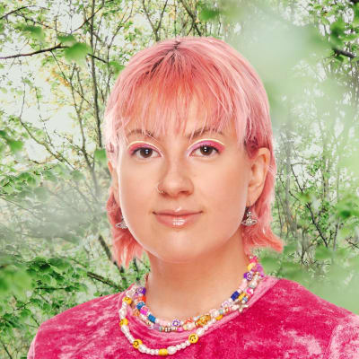 Ronja Stanley småler mot kameran. I bakgrunden syns en grönskande skogsdunge.