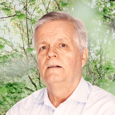 Torbjörn Kevin ser rakt in i kameran. I bakgrunden syns grönskande buskar.