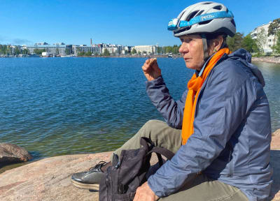 Angela Oker-Blom äter en smörgås och tittar mot havet på Drumsö. 