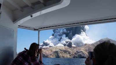 Turist fotograferar Whakaari under ett utbrott den 9 december 2019.