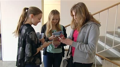 Flickor knapprar på telefonen i Åshöjdens skola i Helsingfors.