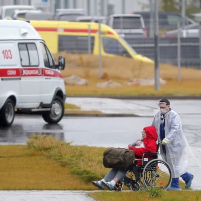 En sjukvårdare i skyddsdräkt rullar in en patient till ett sjukhusavdelning för covid-19-patienter i Moskva.
