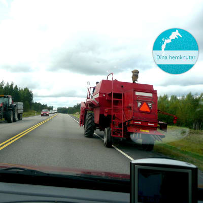 En tröska och en traktor stoppar upp trafiken i båda filerna på den asfalterade vägen som omges av skog. Uppe i högra hörnet finns en stämpel där det står Dina hemknutar.