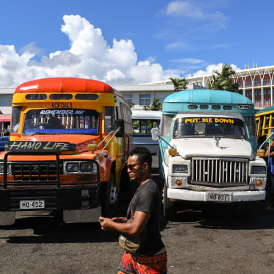 Mies kävelee bussien ohi Samoan pääkaupungissa Apiassa.