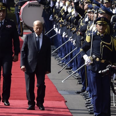 Michel Aoun på en röd går förbi tre rader med soldater i paraduniform.