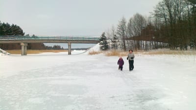 Två personer springer på isen under bron till Hyppeis i Houtskär