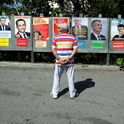 En man tittar på valaffischer i Saint-André-de-la-Roche, nära Nice den 10 april 2017 inför det franska presidentvalet.