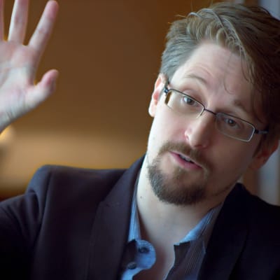 Edward Snowden med ena handen uppsträckt  i ett hotellrum i Moskva  / April 2019, Moskva 
