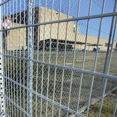 Direktören för Tavastehus fängelse Samuli Laulumaa står lutad mot fängelsets gallerstaket.