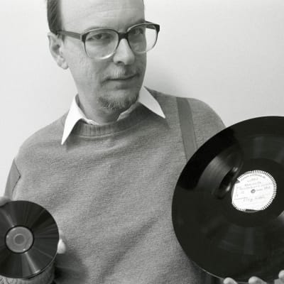 Pekka Gronow kädessään cd-levy ja pikatallenuslevy