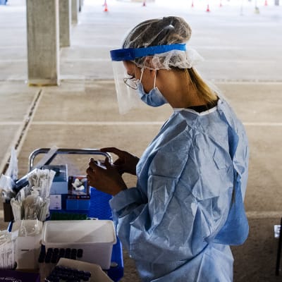 En sjukskötare i skyddsutrustning hanterar ett coronatest.