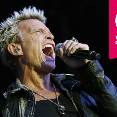 Billy Idol sjunger i en mikrofon som han håller i handen.