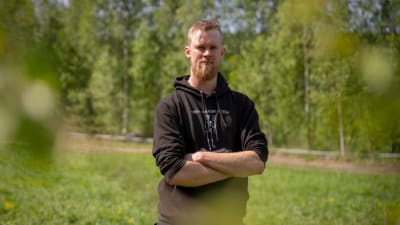 Porträtt av en man som står i sommargrönskan på en grön åker.