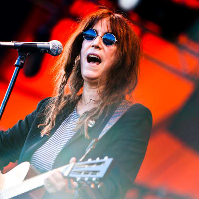 Patti Smith spelar akustisk gitarr och sjunger i en mikrofon.