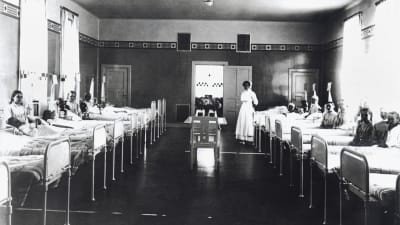 Kvinnor som ligger i sina sängar i en sjukhussal år 1910