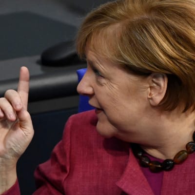 Angela Merkel tittar åt sidan och håller upp ett finger
