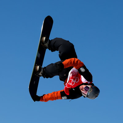 Rene Rinnekangas ilmassa Pekingin olympialaisten slopestylen karsinnassa. Suomalainen on parhaillaan pyörimisliikkeessä ja ottaa grabin lautansa pohjasta.