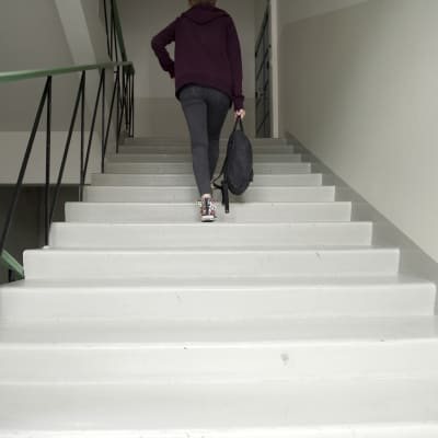 Nuori nainen käytävän portaissa.