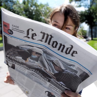 Kvinna läser franska dagstidningen Le Monde.