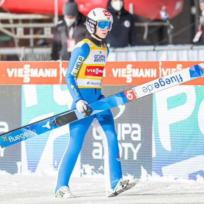 Halvor Egner Granerud går med skidorna i händerna.