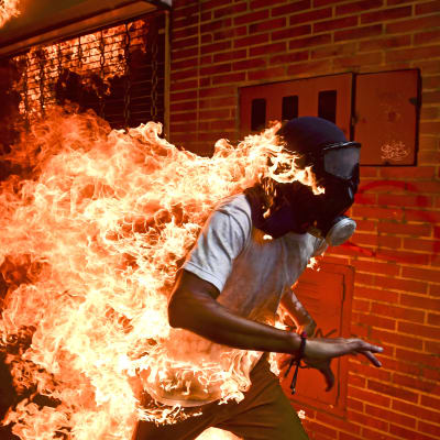 Voittokuva on otettu Venezuelassa Caracasissa protestien aikaan. Kuvassa tuleen syttynyt protestoija 28-vuotias Jose Victor Salazar Balza juoksee katuja pitkin kaasunaamari päässään.