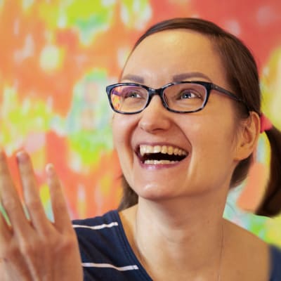 Teija Kangasvieri hymyilee kättään heiluttaen. Hänen hiuksensa ovat saparoilla. 