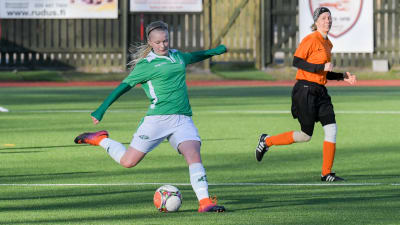 En ung kvinna i vita shorts och grön tröja spelar fotboll i Ekenäs IF. Hon heter Rebecka Mannström.