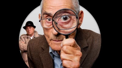 En gammal man i närbild tittar in i kameran med ett förstoringsglas. I bakgrunden syns en annan man.