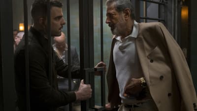 Jeff Goldblum och Zachary Quinto i rollen som skurkar står på varsin sida om en gallerförsedd grind.