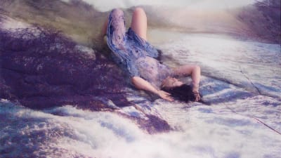 Kvinna ligger på rygg i något som liknar vattenfall.